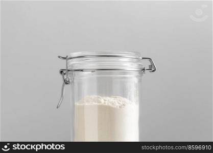 food storage, eating and cooking concept - close up of jar with wheat flour on grey background. close up of jar with wheat flour