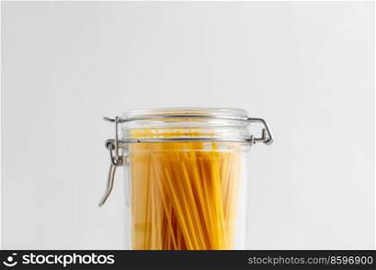 food storage, eating and cooking concept - close up of jar with pasta on white background. close up of jar with pasta on white table