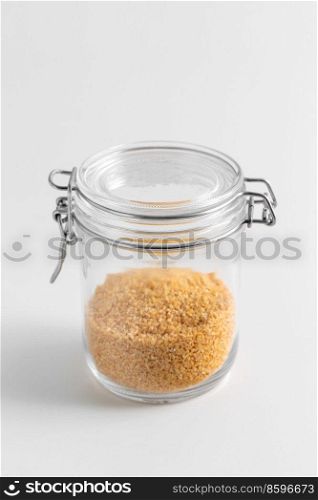 food storage, eating and cooking concept - jar with bulgur on white background. close up of jar with bulgur on white table