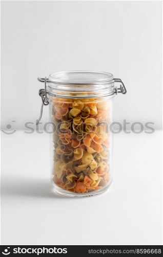 food storage, eating and cooking concept - jar with pasta on white background. close up of jar with pasta on white table