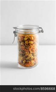 food storage, eating and cooking concept - jar with pasta on white background. close up of jar with pasta on white table