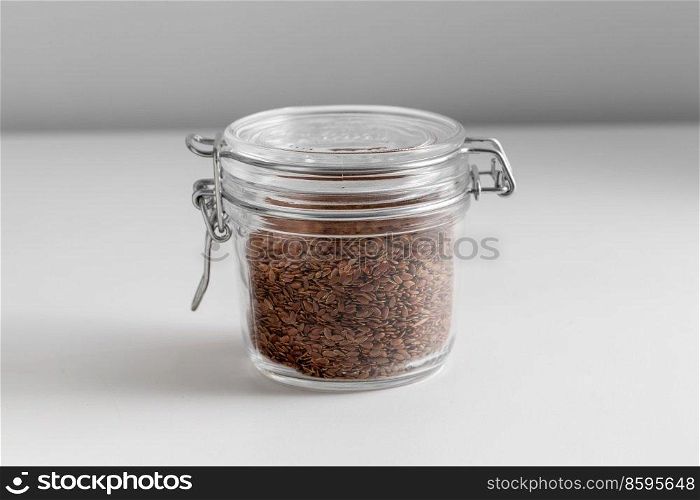 food storage, healthy eating and diet concept - close up of jar with flax seeds on white background. close up of jar with flax seeds on white table