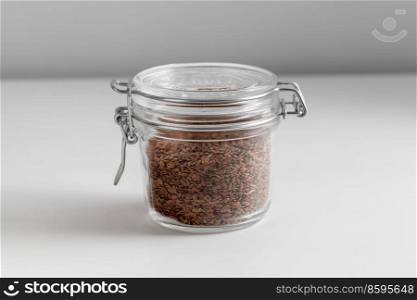 food storage, healthy eating and diet concept - close up of jar with flax seeds on white background. close up of jar with flax seeds on white table