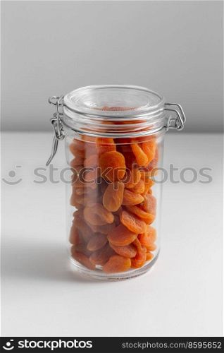food storage, healthy eating and diet concept - jar with dried apricot on white background. close up of jar with dried apricot on white table