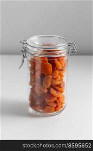 food storage, healthy eating and diet concept - jar with dried apricot on white background. close up of jar with dried apricot on white table
