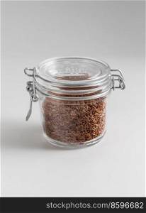 food storage, healthy eating and diet concept - jar with flax seeds on white background. close up of jar with flax seeds on white table