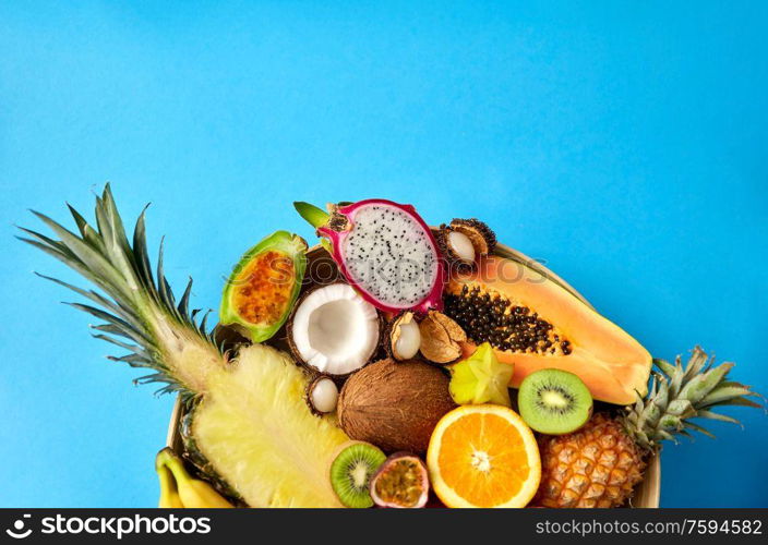 food, summer and healthy eating concept - close up of plate of different exotic fruits on blue background. plate of exotic fruits on blue background