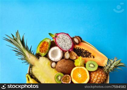 food, summer and healthy eating concept - close up of plate of different exotic fruits on blue background. plate of exotic fruits on blue background