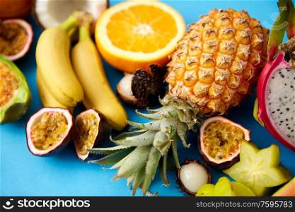 food, summer and healthy eating concept - different exotic fruits on blue background. different exotic fruits on blue background