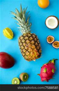 food, summer and healthy eating concept - pineapple with other exotic fruits on blue background. pineapple with other fruits on blue background