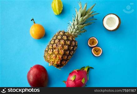 food, summer and healthy eating concept - pineapple with other exotic fruits on blue background. pineapple with other fruits on blue background