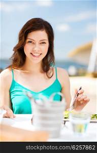 food, summer holidays and vacation - girl eating in cafe on the beach