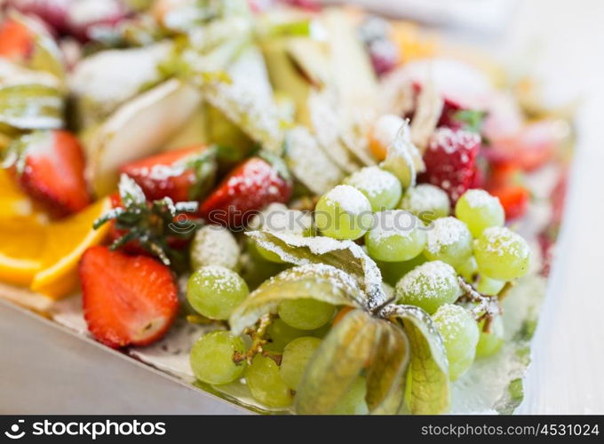 food, sweets and holidays concept - close up of dish with sugared fruit dessert