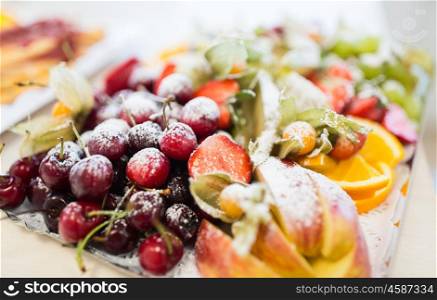 food, sweets and holidays concept - close up of dish with sugared fruit dessert