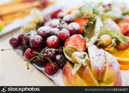 food, sweets and holidays concept - close up of dish with sugared fruit dessert
