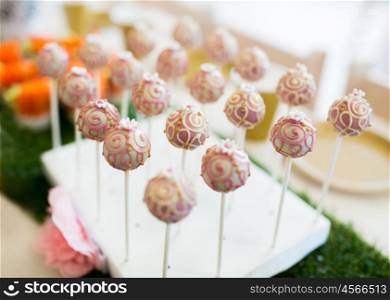 food, sweets, junk-food, holidays and celebration concept - close up of cake pops or lollipops on party table