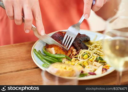 food, thanksgiving day and people concept - hands of woman with fork eating roast chicken at wooden table. hands of woman with fork eating roast chicken