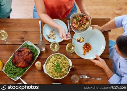food, thanksgiving day, eating and leisure concept - people with salad having dinner. people eating salad at table with food