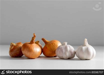 food, vegetable and healthy eating concept - onion and garlic on table. close up of onion and garlic on table