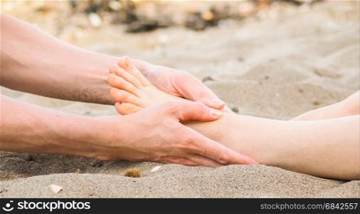 Foot massage on a beach in sand, male and female caucasian