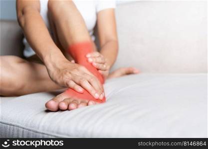 Foot pain, Asian woman sitting on sofa hold her ankle injury feeling pain in her foot at home, female suffering from feet ache use hand massage relax muscle from ankle interior, Healthcare and medical