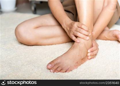 Foot pain, Woman holds her ankle injury feeling pain in her foot at home, female suffering from feet ache use hand massage relax muscle from ankle in home interior, Healthcare problems and medical