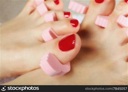 foot pedicure applying woman&#39;s feet with red toenails in toe separators