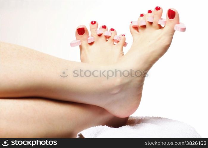 foot pedicure applying woman&#39;s feet with red toenails in toe separators white background