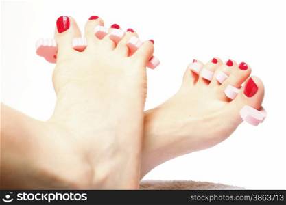 foot pedicure applying woman&#39;s feet with red toenails in toe separators white background