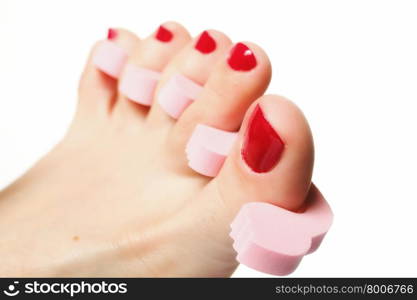 foot pedicure applying woman&#39;s feet with red toenails in toe separators white background