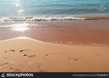Foot prints on a sandy beach at sunrise time