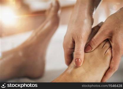 Foot reflexology massage. Female therapist massaging client&rsquo;s foot at wellness salon. Foot Reflexology Massage
