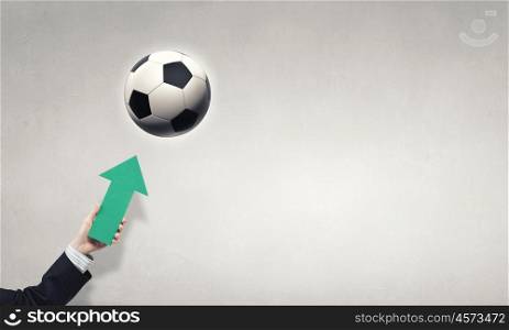 Football. Close up of businessman hand holding arrow and pointing at ball