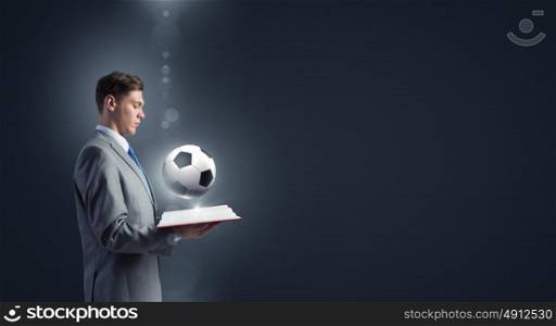Football coach. Young businessman with book in hands and ball