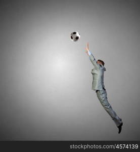 Football fan. Businessman in suit catching soccer ball in jump