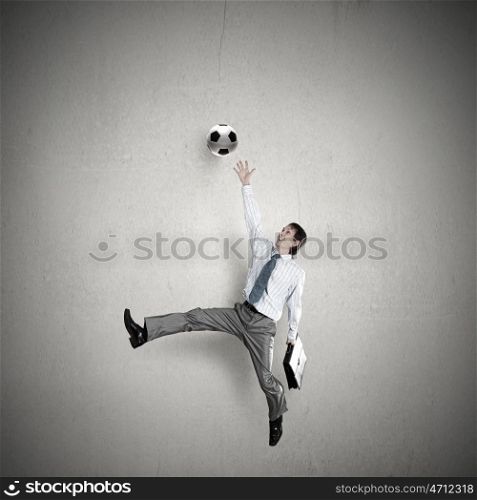 Football fan. Businessman in suit catching soccer ball in jump