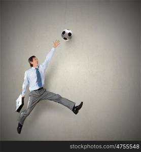 Football fan. Businessman in suit catching soccer ball in jump