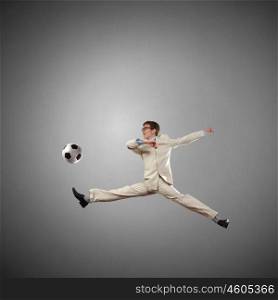 Football fan. Businessman in suit hitting soccer ball in jump