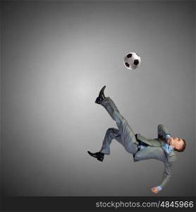 Football fan. Businessman in suit hitting soccer ball in jump