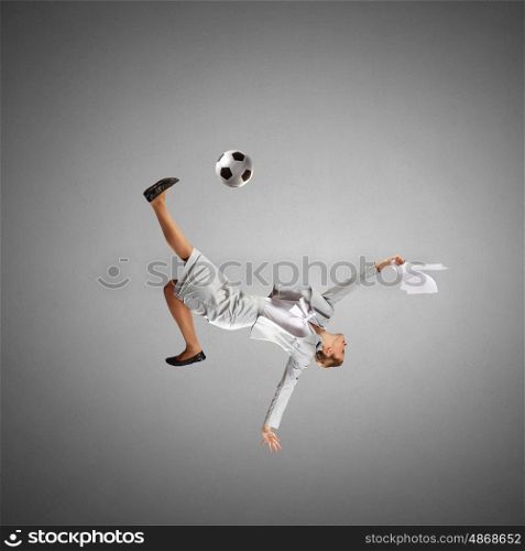 Football fan. Full length businesswoman in jump kicking a soccer ball