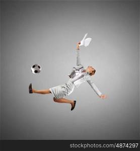 Football fan. Full length businesswoman in jump kicking a soccer ball