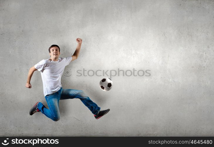 Football fan. Man in casual kick football ball over head