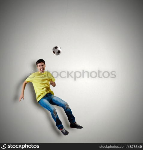 Football fan. Man in casual kick football ball over head