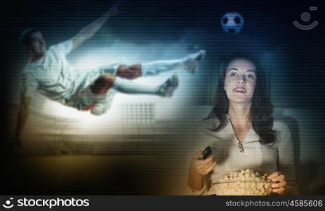 Football fan. Young girl holding popcorn and watching football match on telly