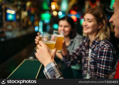 Football fans drinks light beer at the counter in sports bar. Tv broadcasting, young friends celebrates win of the favorite team, success game celebration in pub