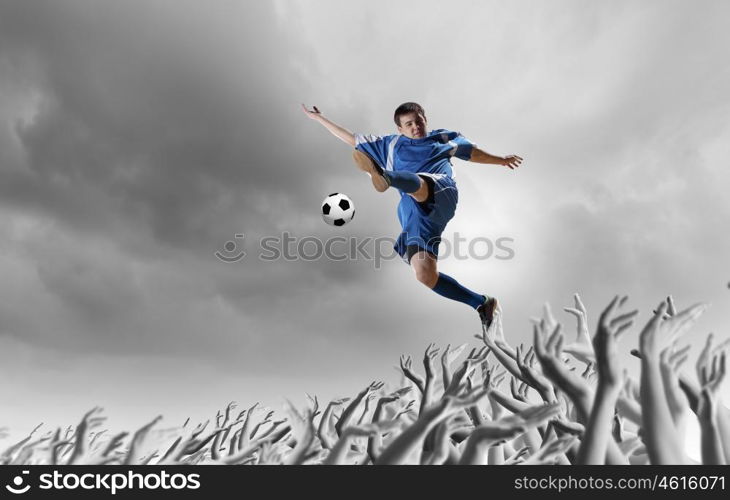 Football fans. Football player in jump kicking the ball supported by fans