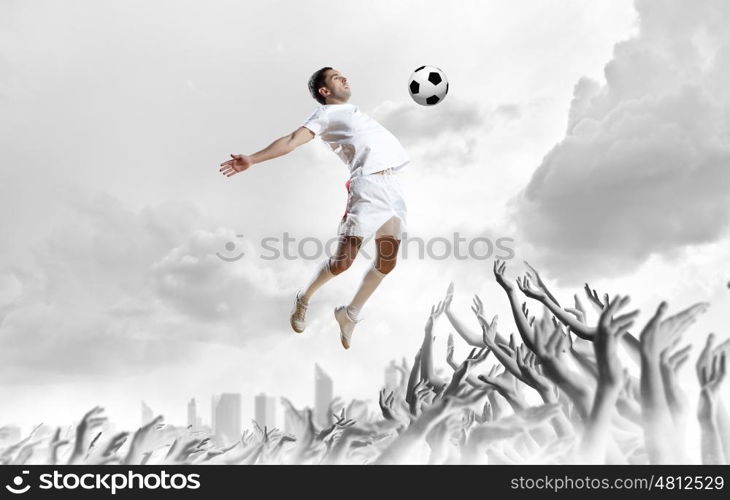 Football fans. Football player in jump kicking the ball supported by fans