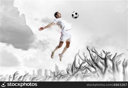 Football fans. Football player in jump kicking the ball supported by fans