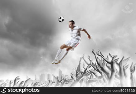 Football fans. Football player in jump kicking the ball supported by fans