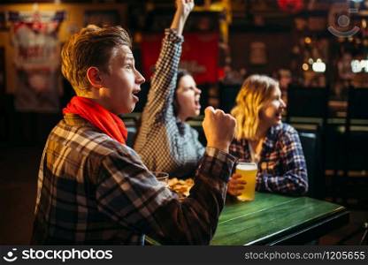 Football fans watching match and rejoice scored a goal in sports bar. Tv broadcasting, young friends leisures in pub